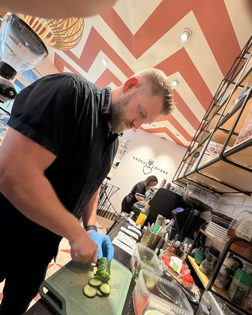 A team member slicing cucumber in blue gloves at the bar