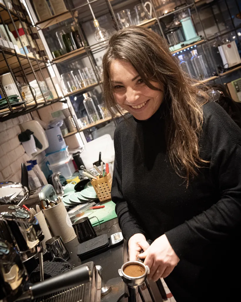 A barista tamping espresso at the bar, smiling